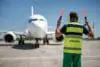 Airport Worker In Headphones Meeting Passenger Plane