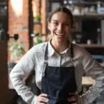 Cheerful Young Waitress Wearing Apron Laughing Looking At Camera