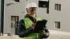 Elderly African American Man Construction Manager Evaluates Building Old Foreman Standing On Street In Protective Hardhat Writes Data To Tablet Engineer Builder Thinks Over Work Plan Closeup Outdoors