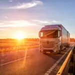 Modern Wagon Truck Transports Cargo Against The Backdrop Of A Sunset. The Concept Of Truck Drivers In The Field Of Freight And Logistics, Copy Space
