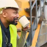 Coffee, Engineer And Construction Worker Relax On Break At Construction Site, Smiling And Inspired By Building Idea And Vision. Engineering, Motivation And Black Man Happy About Project Development