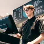 Young Waiter Serving Customer At Cash Point In Cafe. Man Working With Pos Terminal. Cashier, Barista Checking For Payment Receipt. Hospitality, Server And Preparing A Slip At The Till In Coffee Shop