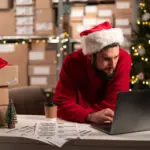 Male Online Store Small Business Owner Entrepreneur Seller Checking Orders Using Laptop Preparing Delivery Parcel On Table. Christmas Sale. Dropshipping Concept.