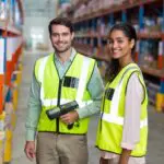 Portrait Of Smiling Warehouse Workers Scanning Box
