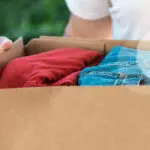 Man Holding Cardboard Box With Clothes Inside. Concept Donation