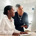 Computer, Teamwork And Review With Business Women In Office For Accounting Discussion, Audit Feedback Or Talk. Tech, Portfolio Manager And Collaboration With Mentor, Tablet And Finance Agency Report