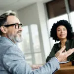 Professional Business Discussion Between Mature Man And Young Woman In A Modern Office Setting