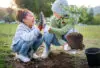 High Five, Child And Woman With Plant For Gardening At Park With Trees In Nature Garden Environment. Happy Volunteer Family Planting For Growth, Ecology And Sustainability For Community On Earth Day