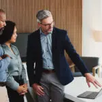 Laptop, Meeting And Business People In Office With Review, Advice Or Feedback On Legal Project. Collaboration, Tech And Team Of Attorneys With Planning, Discussion And Together For Law Case Research