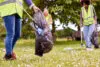 Close Up Of Female Volunteers Picking Up Litter In The Countryside