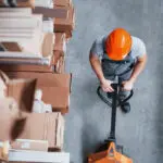 Top View Of Male Worker In Warehouse With Pallet Truck