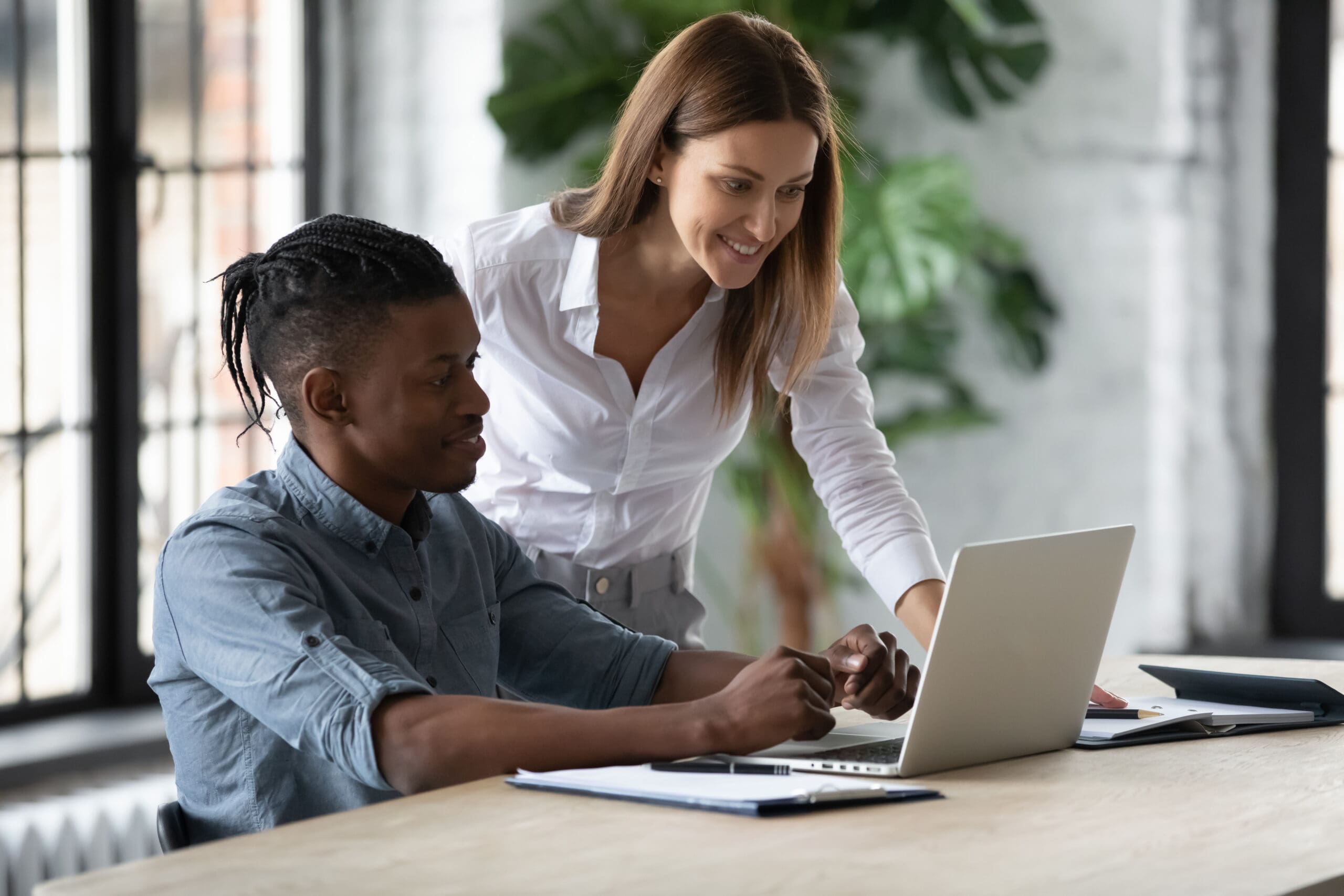 Smiling Businesswoman Mentor Helping New African American Employee With Software