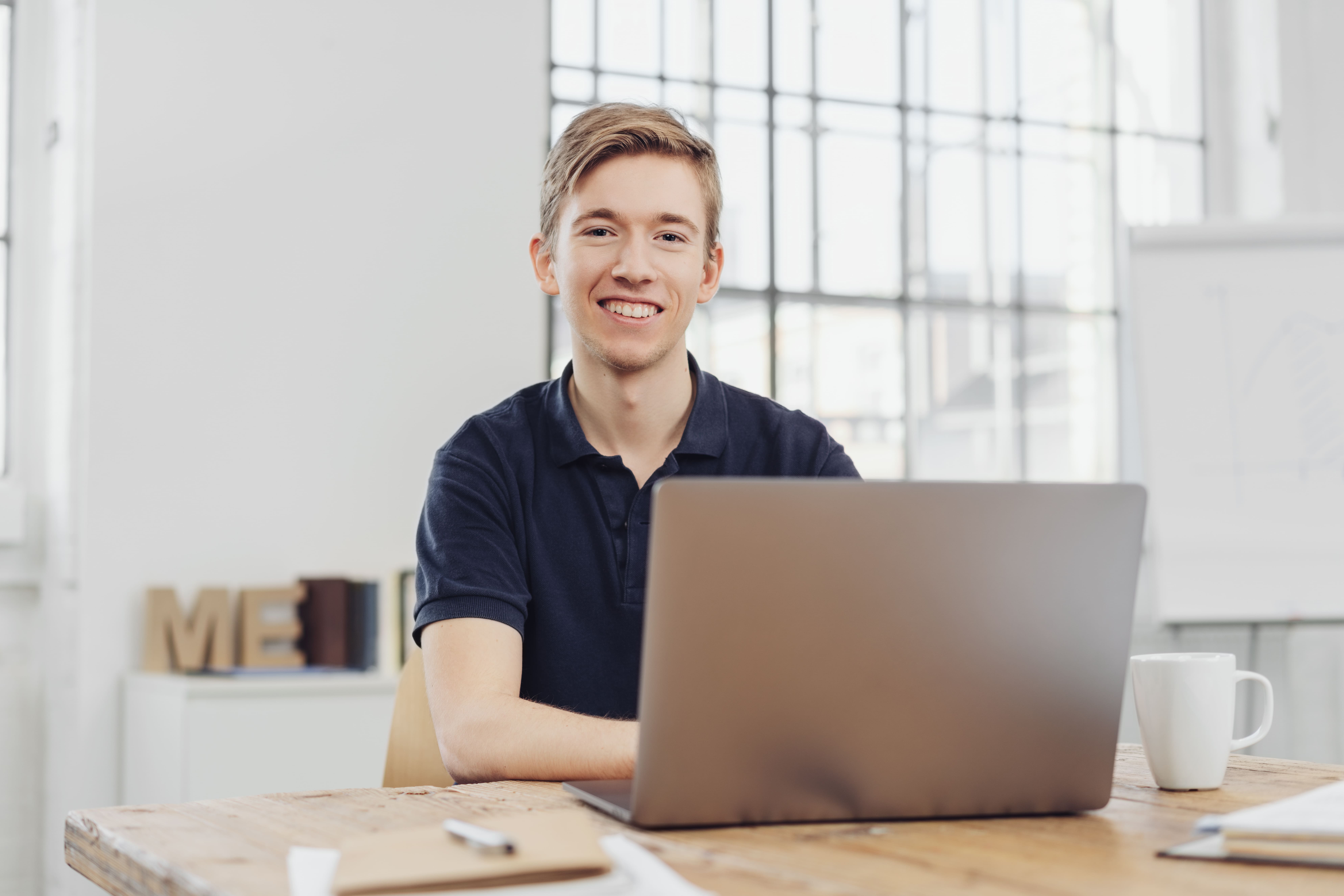 Young Cheerful Man Sitting In Front Of Laptop