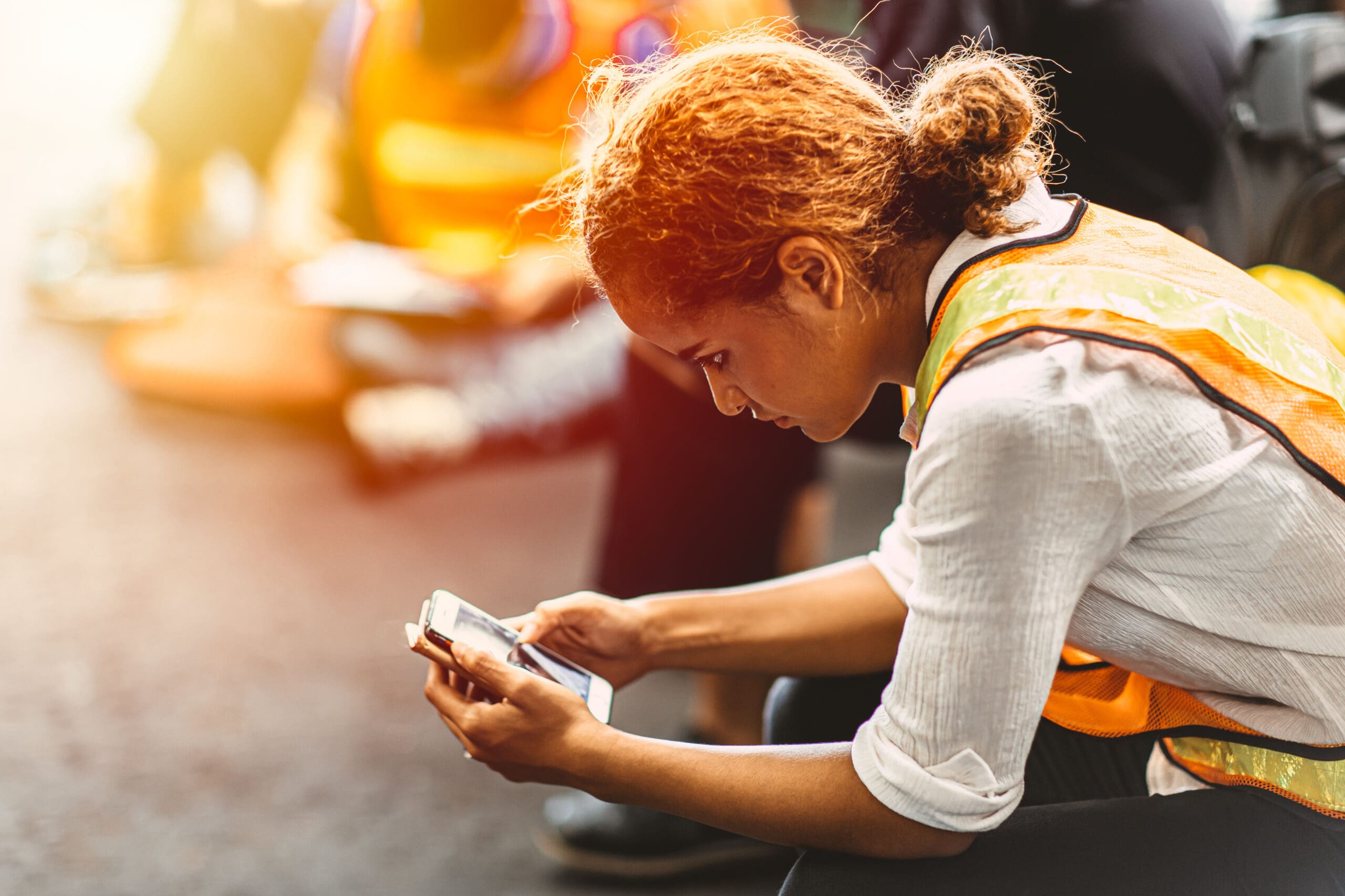Black African American Woman Break Relaxes And Reads The News On Her Mobile Smart Phone In An Industrial Factory.